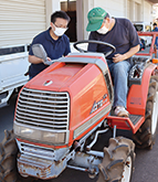 トラクターに乗った生産者と話す職員